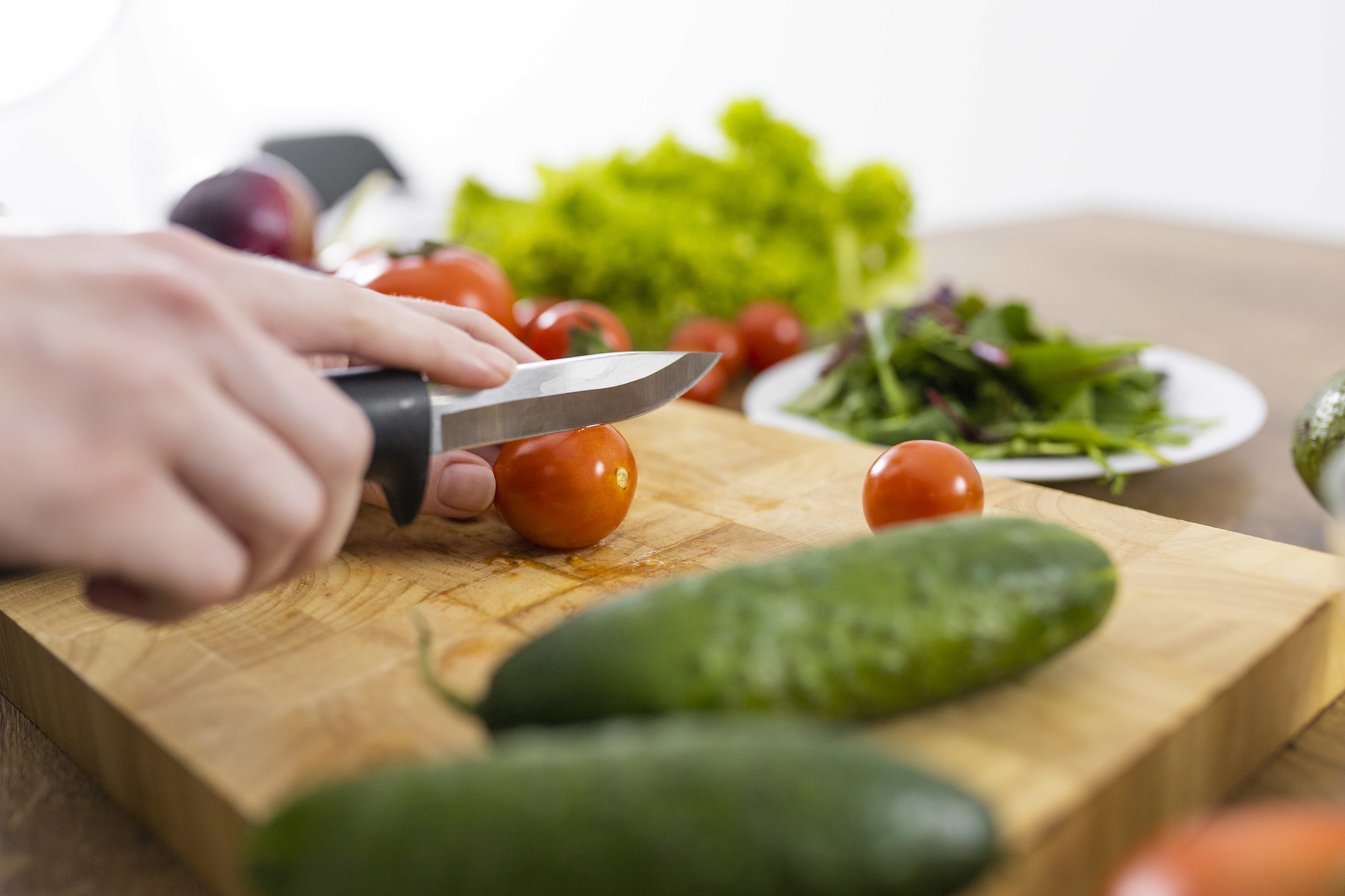 close-up-hand-cutting-tomato-with-knife